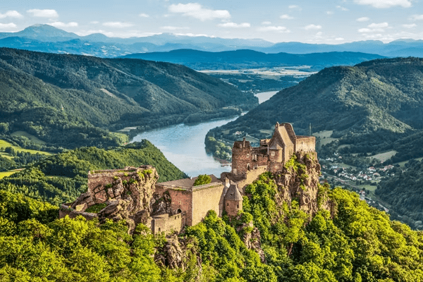 A castle perched above a winding river, overlooking the water from a dramatic elevated landscape.