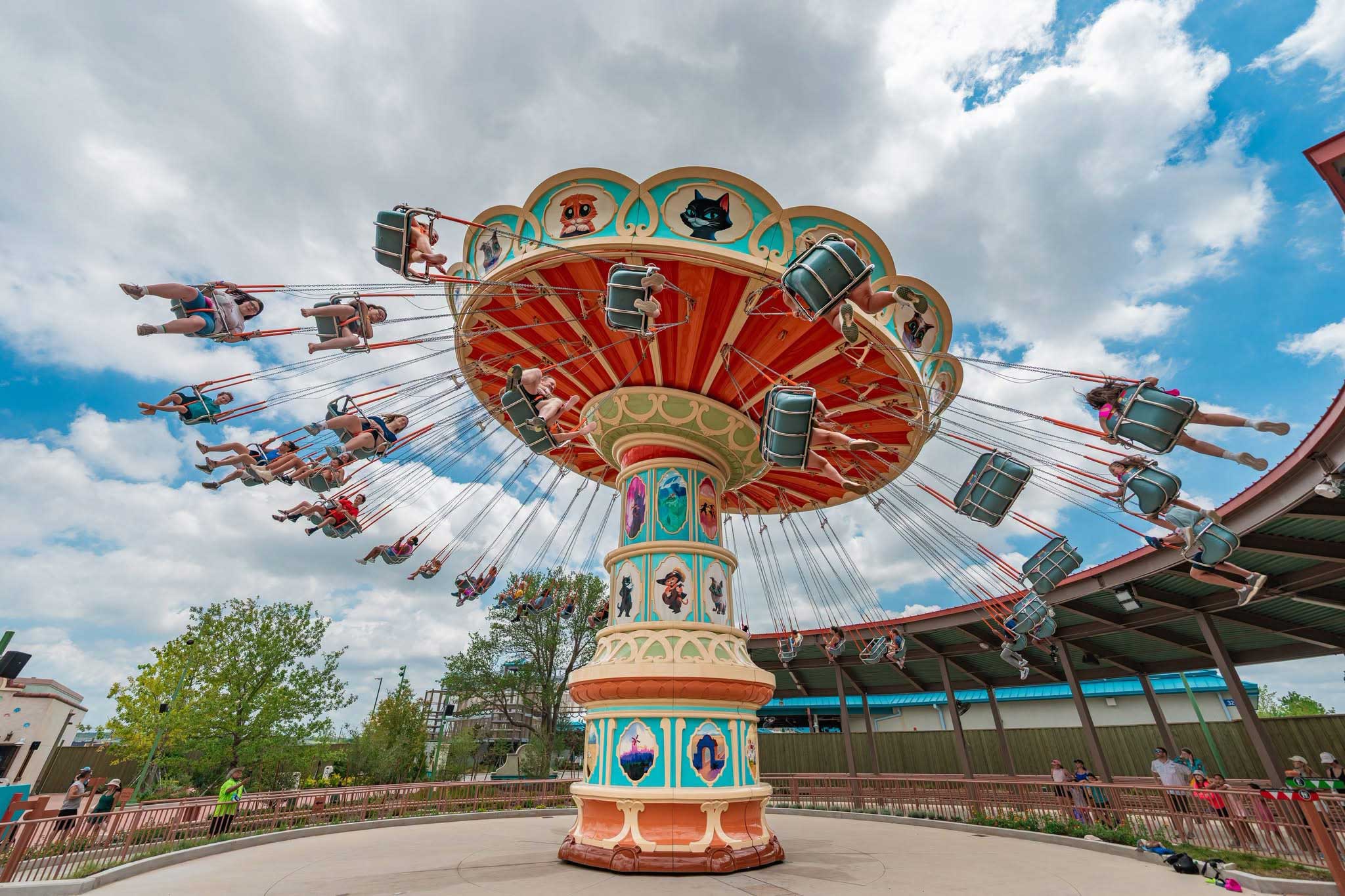Classic theme park swing ride with chairs spinning high in the air against a clear sky