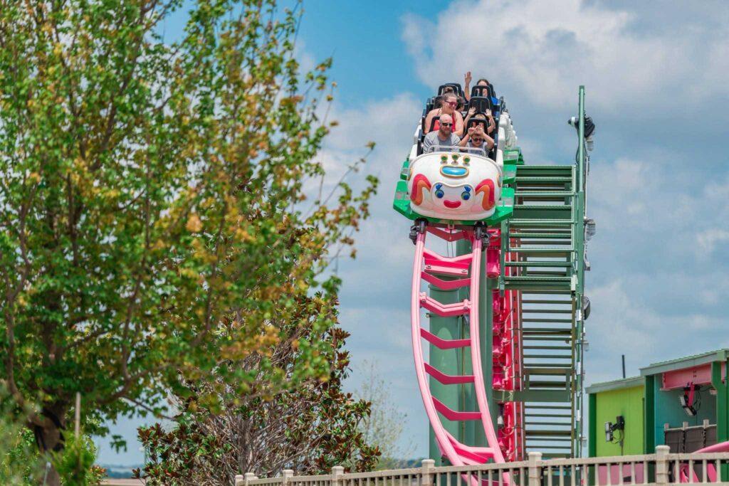 Colorful children’s roller coaster with small cars winding through a bright family-friendly theme park